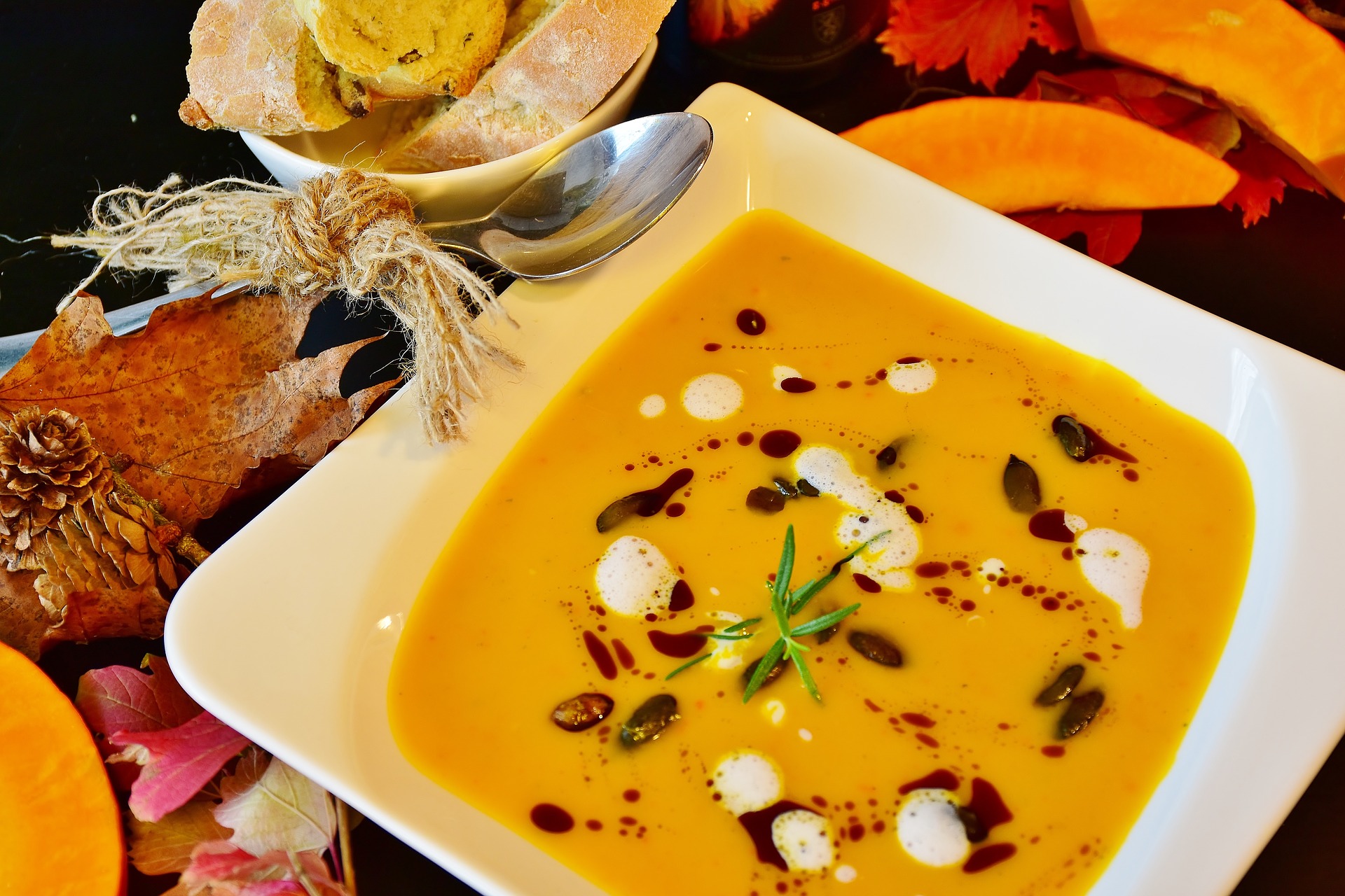 Ein Teller Kürbissuppe an einem herbstlich dekorierten Tisch